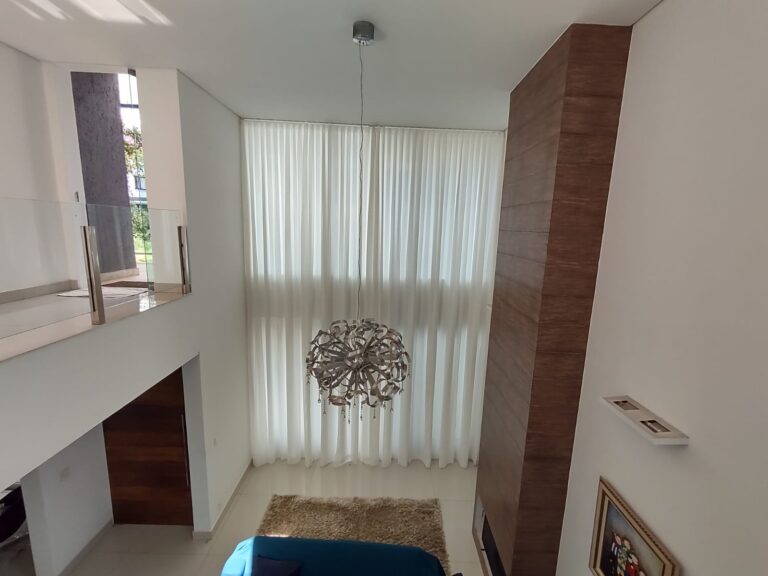 Cortina translúcida em sala com pé-direito duplo: a automação permite controlar a entrada de luz com um comando.
